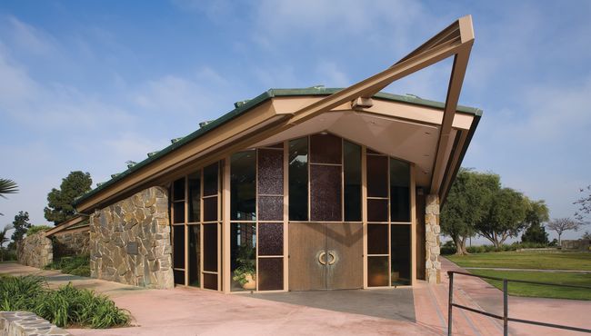The 22-foot-high windows of Hillside Chapel are flanked by cottage-style stone walls at Rose Hills Memorial Park. 